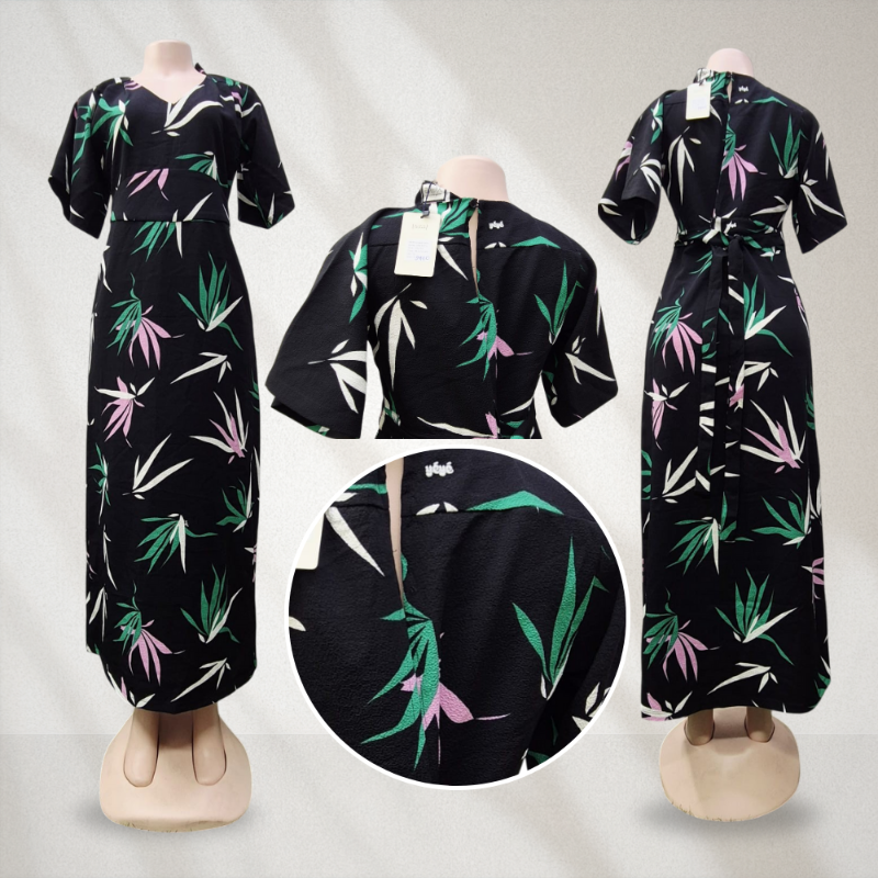 Black dress with green and pink leaf pattern on mannequins against a gray background