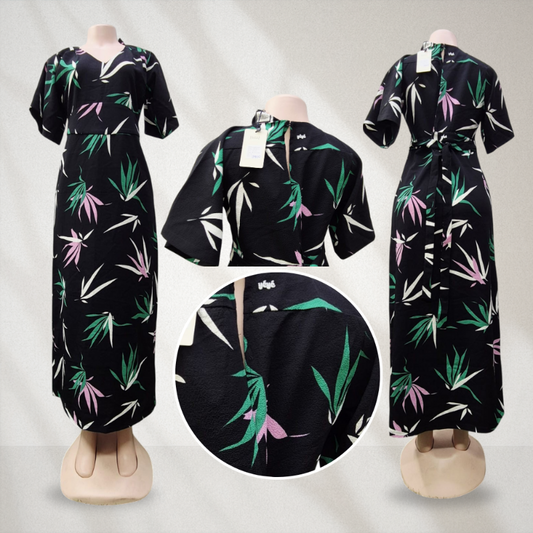 Black dress with green and pink leaf pattern on mannequins against a gray background