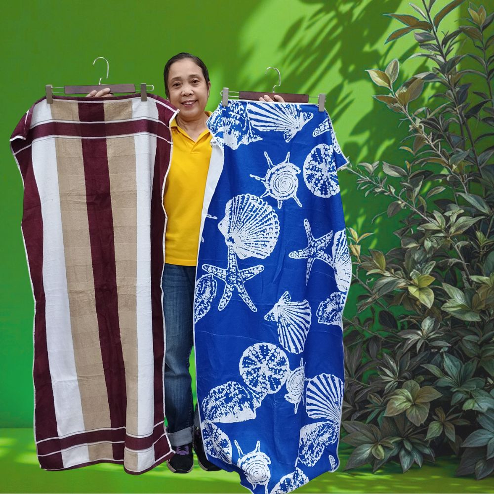 Person holding two beach towels, one striped and one with shell pattern, against a green background.